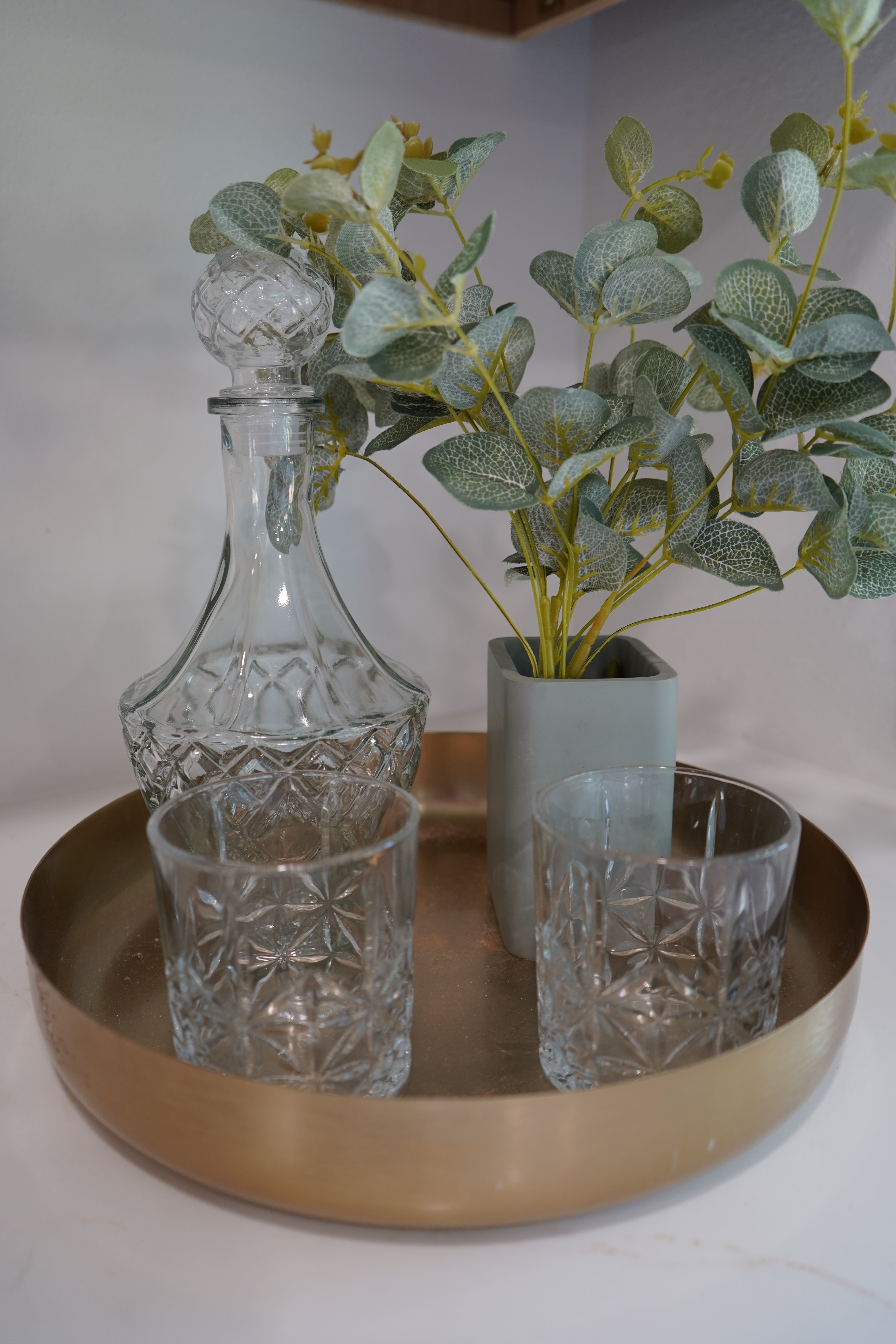 Decorative wall-mounted holder with glass vases and a plant on a plain background