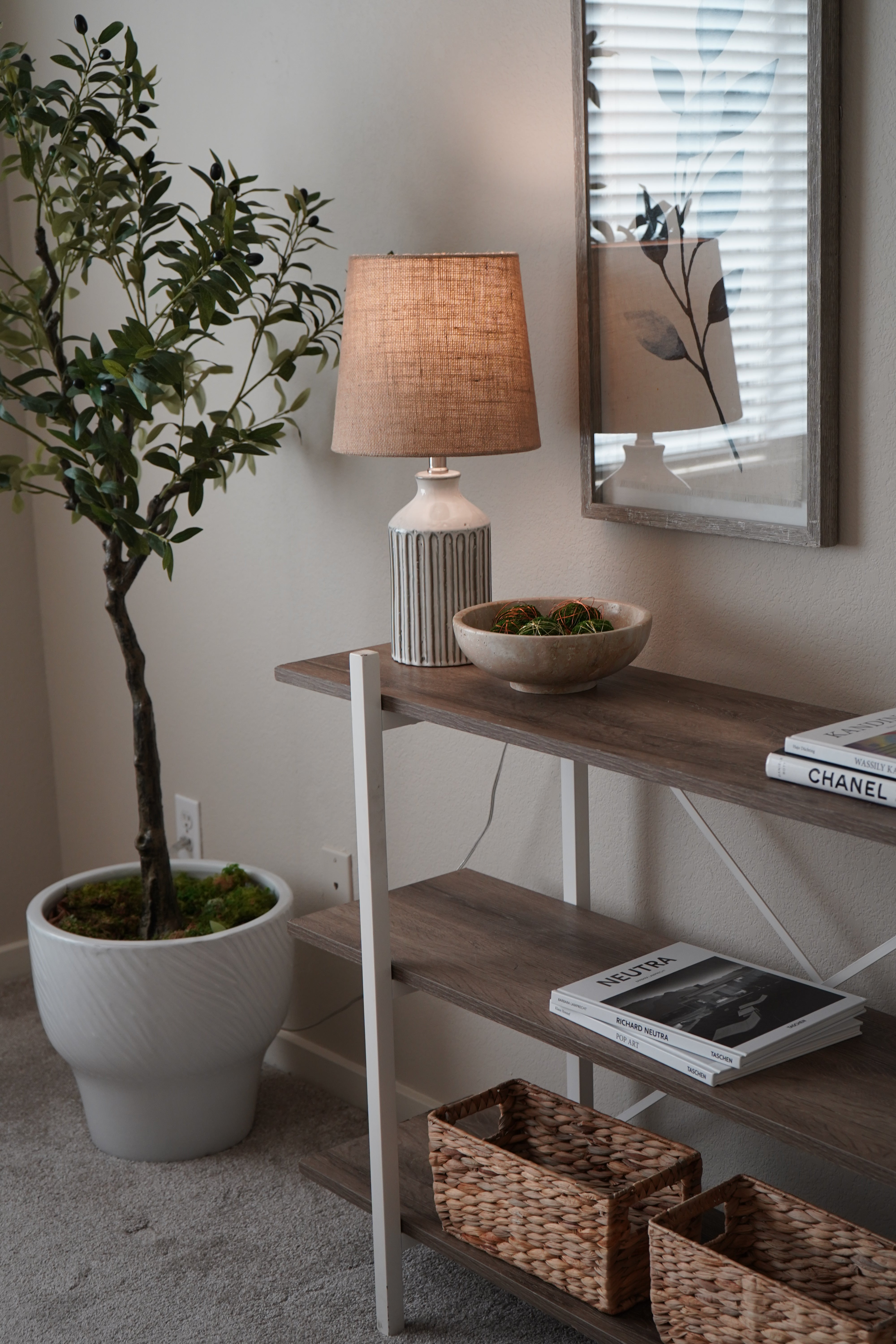 Decorative items including a lamp, mirror, and plant on a surface.