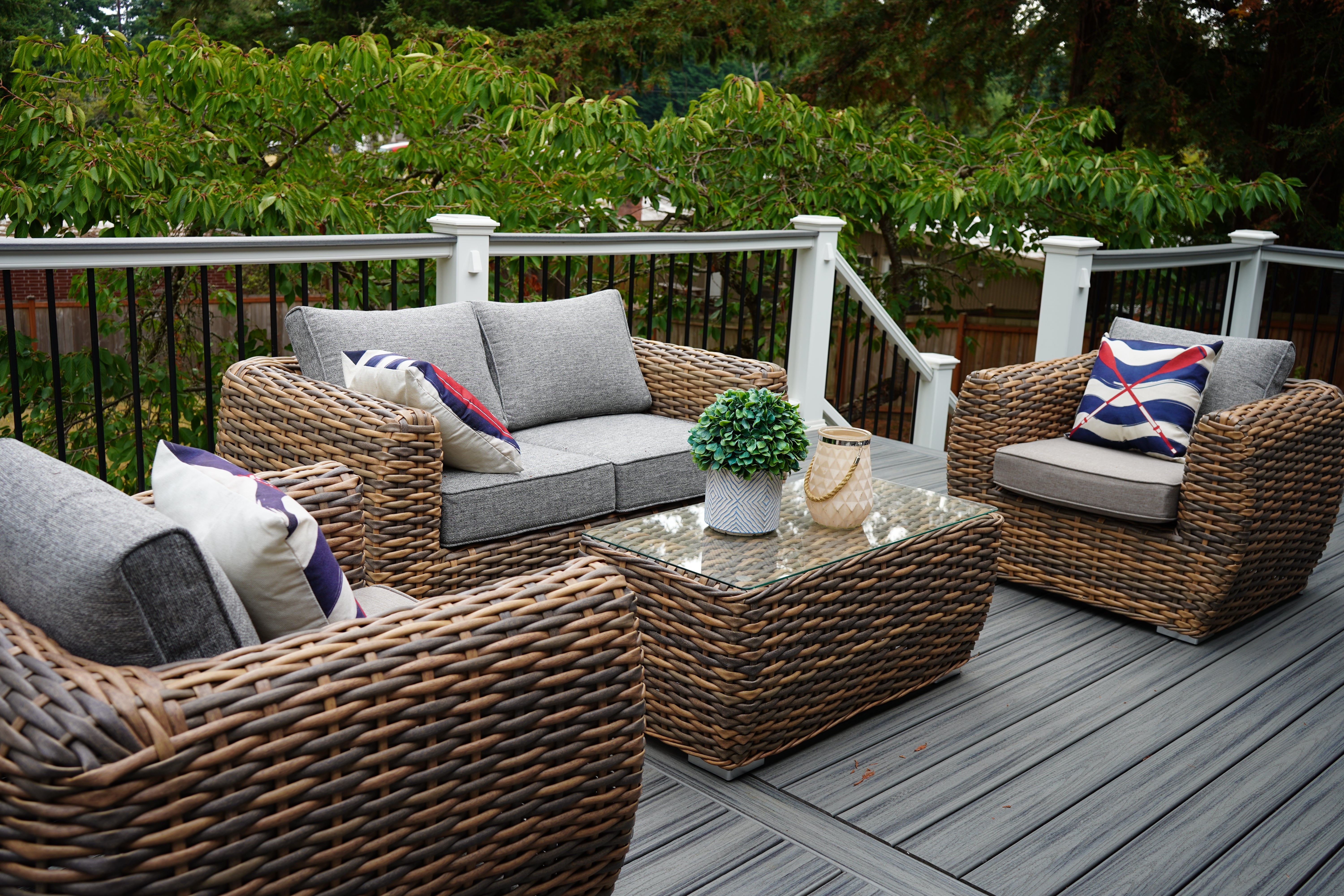 Outdoor patio furniture set with wicker chairs and sofa on a wooden deck.