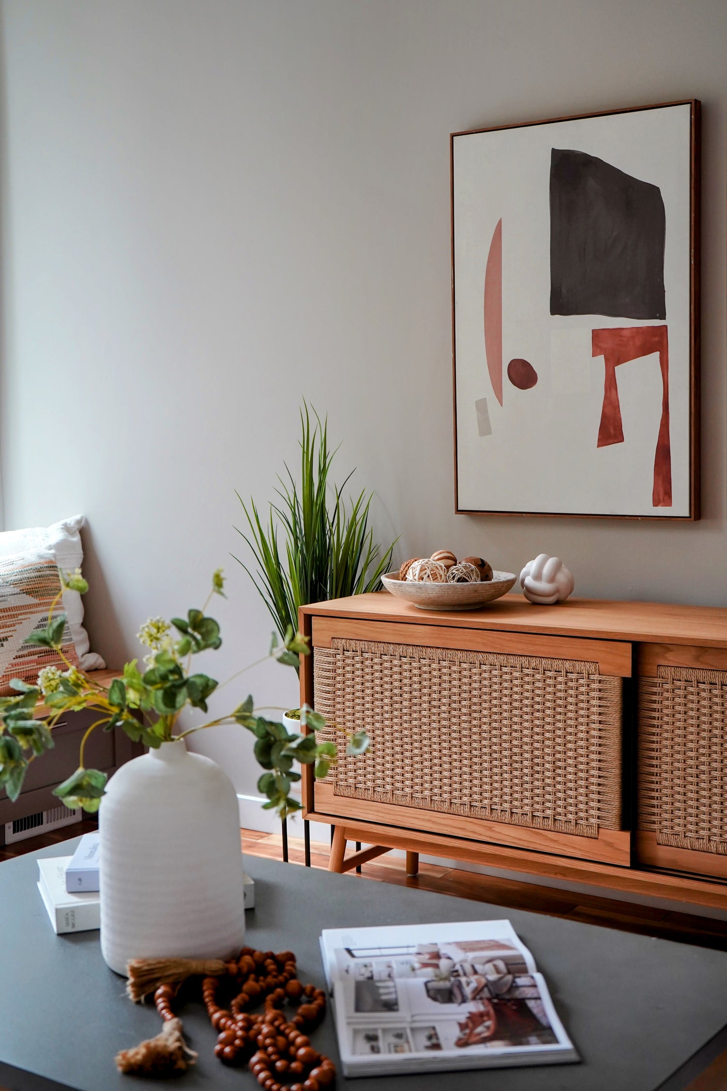 Living room with wooden sideboard, abstract art, and decorative items.