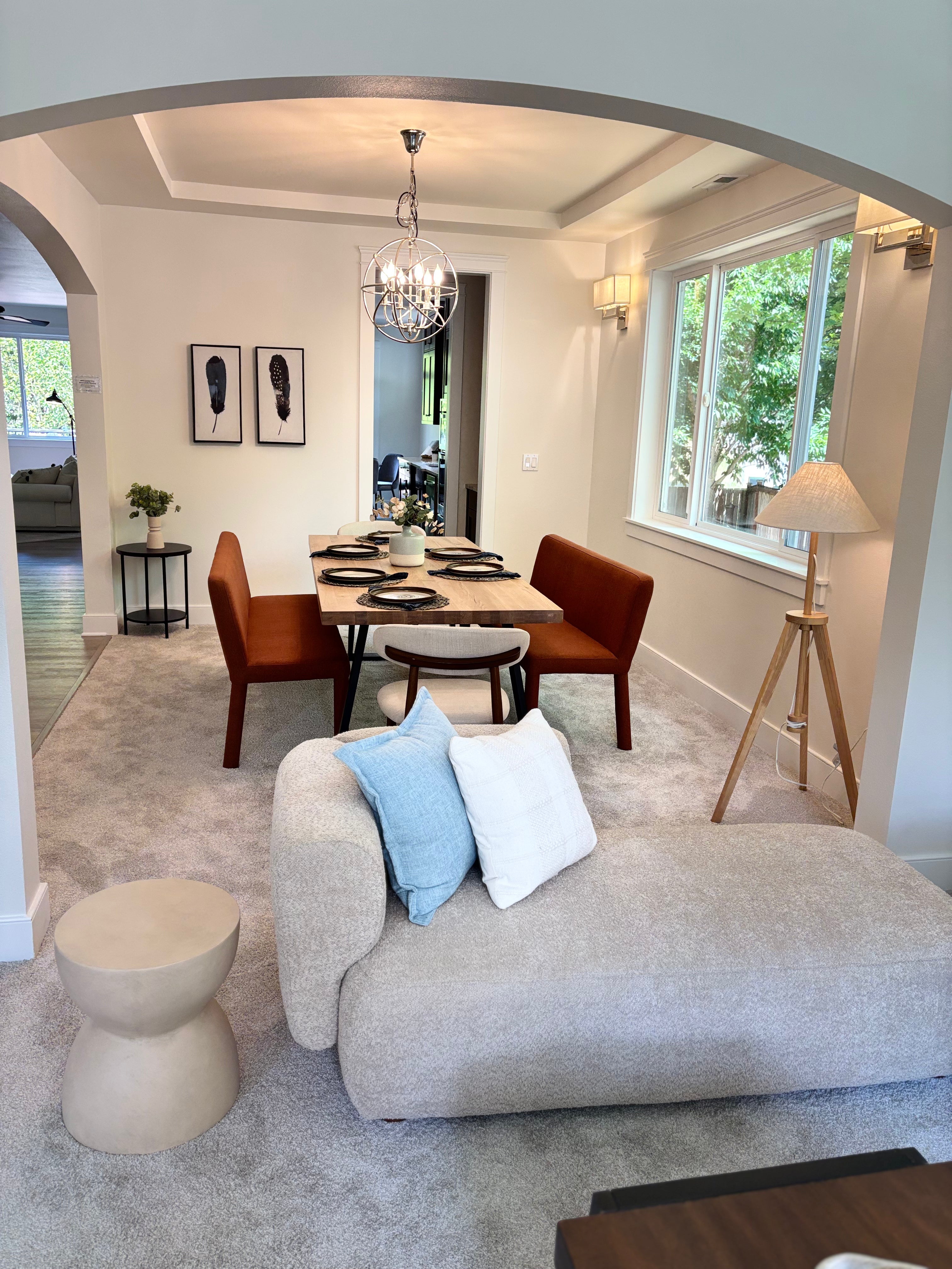 Living room with a beige sofa, blue and white pillows, and a dining table in the background.