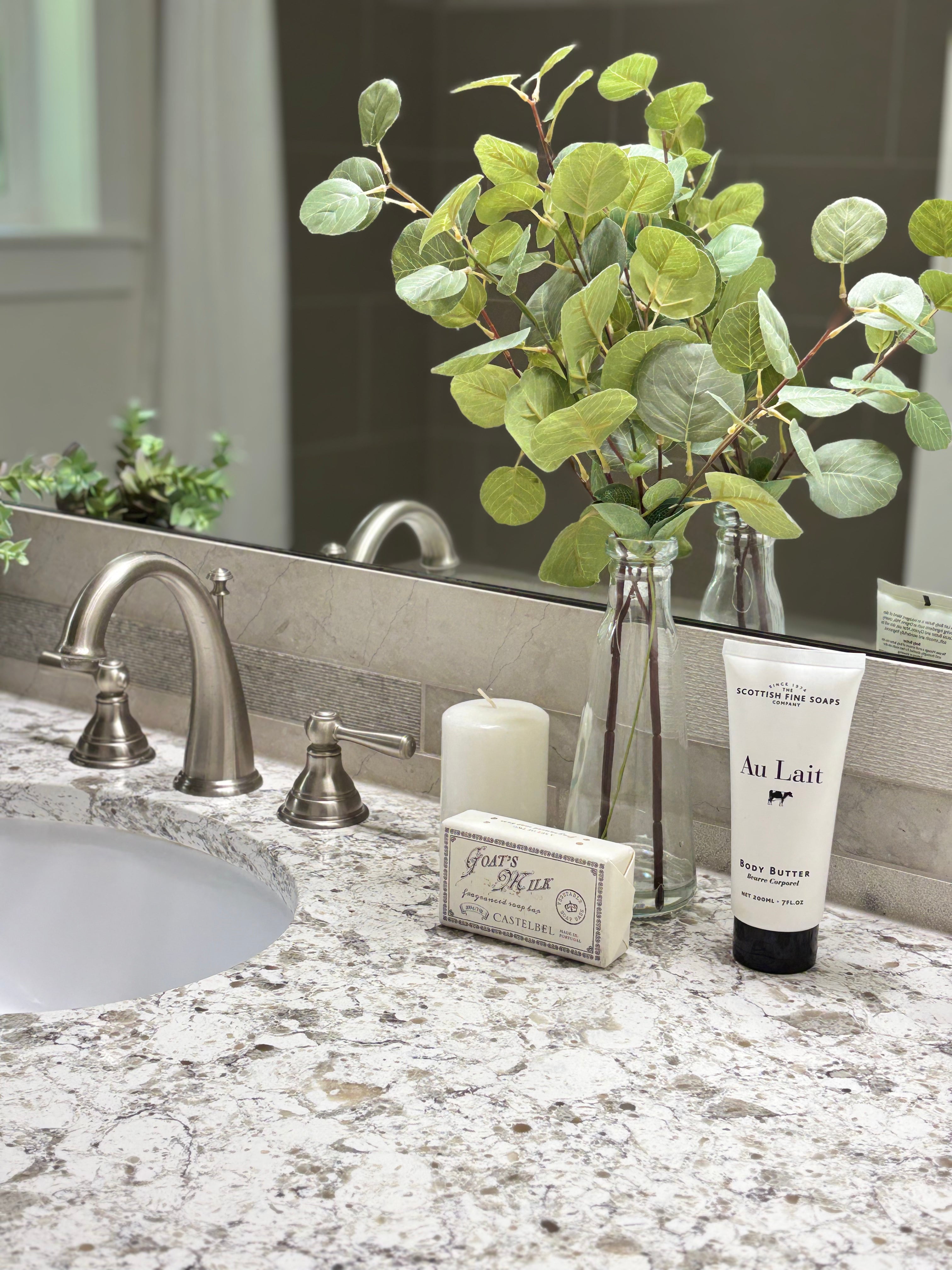 Bathroom counter with sink, faucet, candle, soap, and plant