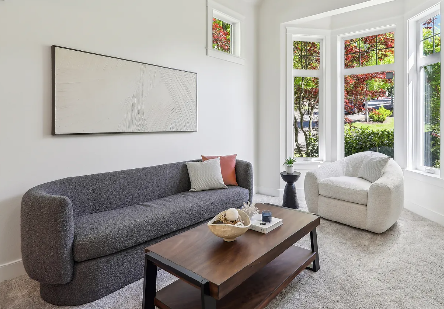 Modern living room with gray sofa, white armchair, and wooden coffee table.